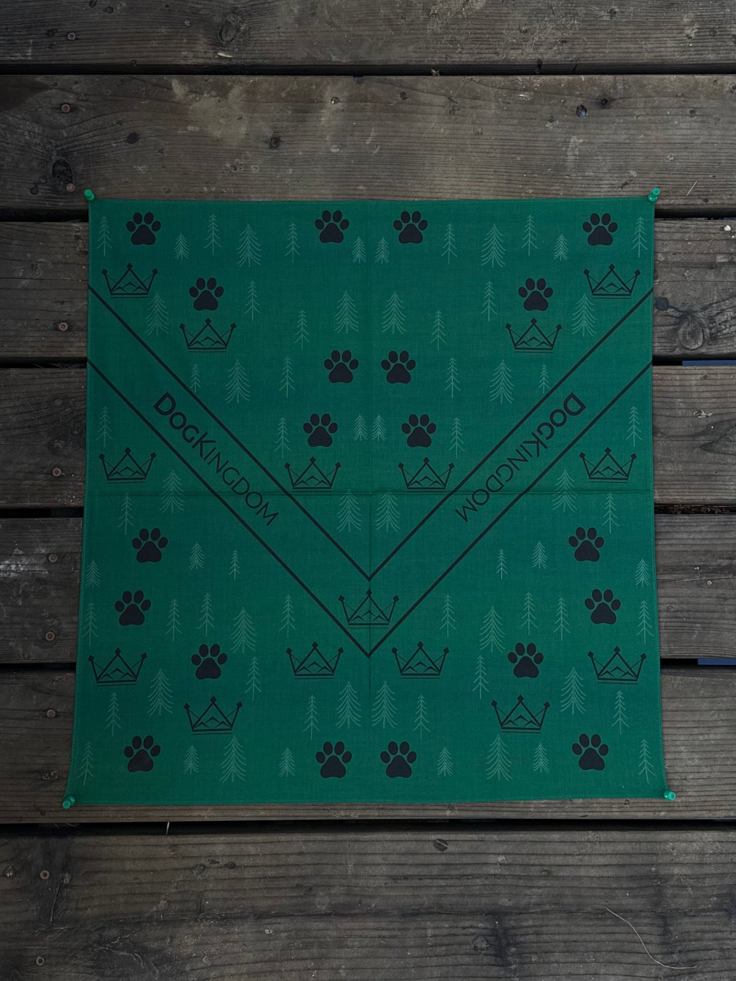 Close-up of DogKingdom cotton dog bandana with paw and crown motifs on wooden surface