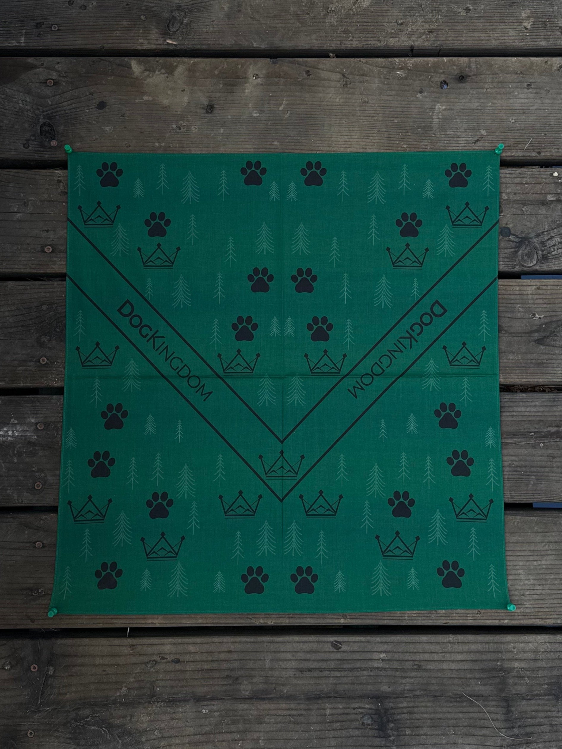 Close-up of DogKingdom cotton dog bandana with paw and crown motifs on wooden surface