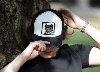 Person wearing DogKingdom Akita trucker hat – embroidered Akita dog patch cap styled outdoors.